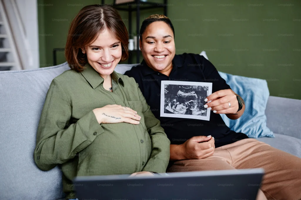 pregnant couple joyfully sharing an ultrasound photo while sitting on a couch at home